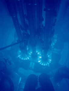 Cerenkovstraling rond een reactorkern. Deze straling, veroorzaakt door subatomaire deeltjes doe sneller reizen dan het licht in (hier) water, komt vaak vrij bij de opwekking van kernenergie.